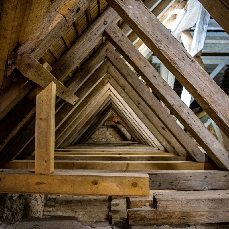 Ancienne charpente en bois de grenier, perspective profonde de poutres triangulaires avec marques sculptées. Vieux et nouveau bois.